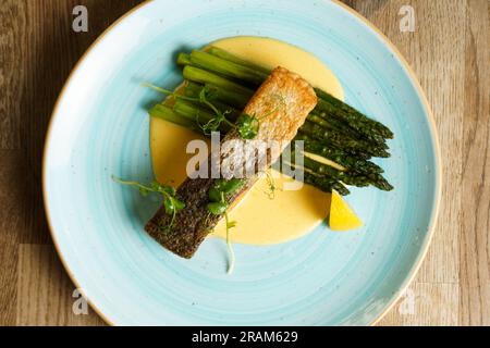 Blick von oben auf gegrilltes Lachsfilet mit gedämpftem grünen Spargel und Sauce Hollandaise. Stockfoto