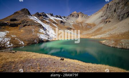 Island Lake mit smaragdgrünem Wasser unter klarem, blauem Himmel und Schnee auf den Bergen | San Juan National Forest, Colorado, USA Stockfoto