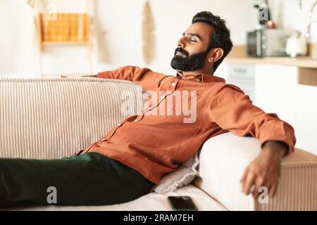 Ein Indianer liegt auf einer bequemen Couch und ruht sich zu Hause aus Stockfoto