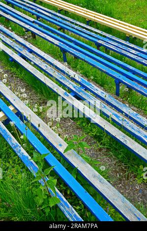 Vier Holzbänke sind blau lackiert, eine ist lackfrei Stockfoto