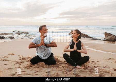 Fröhliche Chefkaukasierin und Mann in Sportbekleidung üben Yoga und Atmung, mentale Übungen, viel Spaß beim Training Stockfoto
