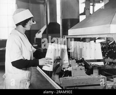 New York, New York: ca. 1928 Mitarbeiter von Sheffield Dairy Farms, die die neuen Papierbehälter von Sealcone verwenden, um Milch zu verpacken und die Glasflasche zu ersetzen. Sie sind leichter, brechen nicht und verstauen aufgrund ihrer konischen Form doppelt so effizient. Hier werden die Behälter mit Paraffin beschichtet, damit sie nicht auslaufen. Stockfoto