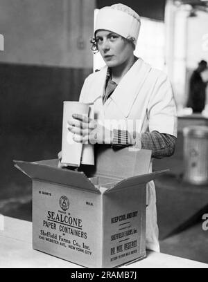 New York, New York: ca. 1928 Mitarbeiter von Sheffield Dairy Farms, die die neuen Papierbehälter von Sealcone verwenden, um Milch zu verpacken und die Glasflasche zu ersetzen. Sie sind leichter, brechen nicht und verstauen aufgrund ihrer konischen Form doppelt so effizient. Hier werden die Container in einer Kiste mit sechs oben und sechs unten verpackt. Stockfoto