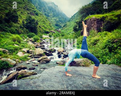 Frau tut Yoga Asana am Wasserfall Stockfoto