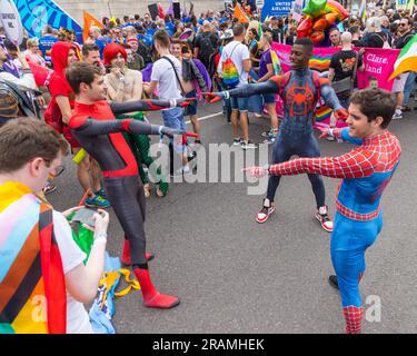 Drei Männer in Spiderman-Kostümen stellen während der "Pride in London"-Parade ein Zeigememe nach Stockfoto