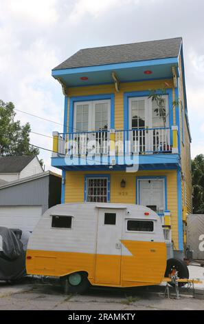 Winziges gelbes zweistöckiges kreolisches Cottage mit blauer Verzierung und gelbem Wohnmobil, New Orleans. Einzigartiges Bild eines Hauses im Stadtteil Faubourg Marigny. Stockfoto