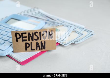 Karte mit Worten Pensionsplan, Banknoten, Taschenrechner und Notizbuch auf weißem Tisch, Nahaufnahme Stockfoto