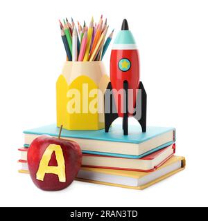Apfel mit geschnitztem Buchstaben A als Klasse. Helle Spielzeugrakete und Schulbedarf auf weißem Hintergrund Stockfoto
