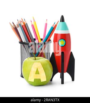 Apfel mit geschnitztem Buchstabe A als Schulklasse. Leuchtende Spielzeugrakete und Bleistifte auf weißem Hintergrund Stockfoto