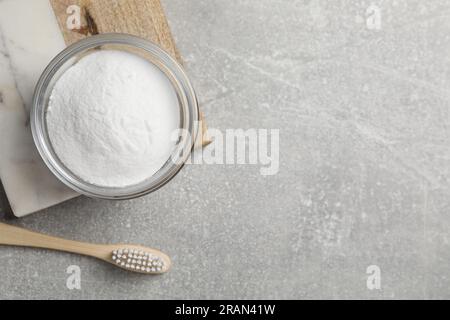 Bambuszahnbürste und Schüssel mit Backpulver auf grauem Tisch, flach liegend. Platz für Text Stockfoto