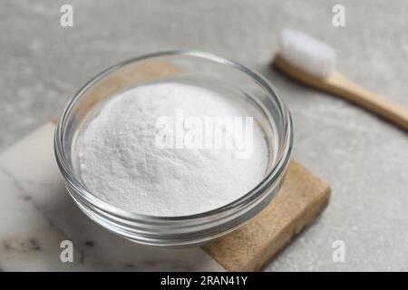 Bambuszahnbürste und Schüssel mit Backpulver auf grauem Tisch, Nahaufnahme Stockfoto