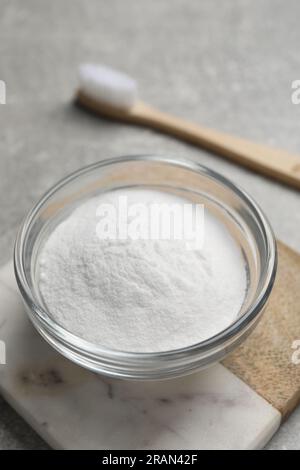 Bambuszahnbürste und Schüssel mit Backpulver auf grauem Tisch, Nahaufnahme Stockfoto