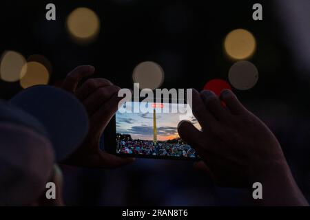 Washington, Usa. 04. Juli 2023. Ein Mann nimmt Videos auf seinem Smartphone auf, während das Feuerwerk in der Nähe des Washington Monument an der National Mall losgeht, während die Menschen am Dienstag, den 4. Juli 2023, Amerikas Unabhängigkeitstag 247. in Washington, DC feiern. Foto: Ken Cedeno/UPI Credit: UPI/Alamy Live News Stockfoto