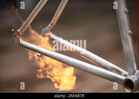 Verwendung des Feuers einer Lötlampe zur Entfernung der Farbe eines Fahrradrahmens, der in einer Fahrradwerkstatt renoviert wird. Stockfoto