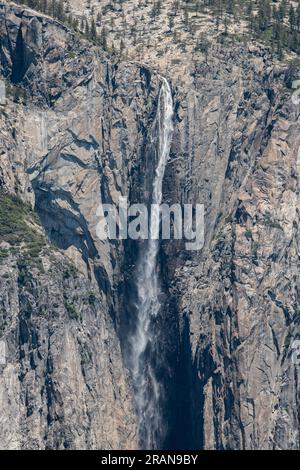 Ein Fluss, der von einer Klippe fließt, und der daraus resultierende Wasserfall im Yosemite-Nationalpark in den Bergen der Sierra Nevada in Kalifornien, USA. Stockfoto