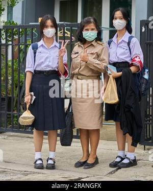 Eine thailändische Lehrerin und ihre Töchter, alle in Schuluniformen gekleidet. Stockfoto