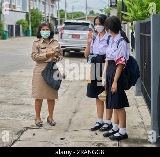 Eine thailändische Lehrerin und ihre Töchter, alle in Schuluniformen gekleidet. Stockfoto