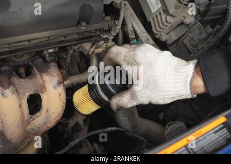 Ein Automechaniker installiert einen neuen Motorölfilter und führt die Wartung eines Pkw durch Stockfoto