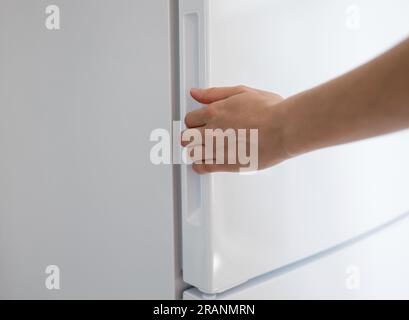 Frau öffnet modernen weißen Kühlschrank. Weiblicher Kühlschrank mit Handöffnung Stockfoto