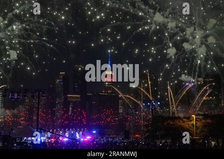 New York, Usa. 04. Juli 2023. NEW YORK, NY - JULI 04: Zuschauer beobachten, wie das Feuerwerk am 4. Juli im Gantry State Plaza Park in Long Island City am 4. Juli 2023 im Stadtteil Queens in New York City explodiert und über das Empire State Building und die Skyline von Manhattan hinausragt. Kredit: Ron Adar/Alamy Live News Stockfoto
