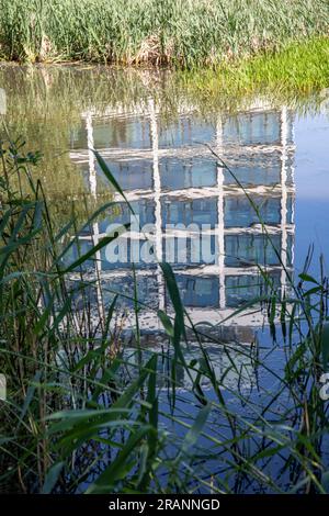 Eine Reflexion des ehemaligen Hauptsitzes der Kone Corporation, heute ein Wohngebäude, aus einem Teich im Munkkiniemi-Viertel in Helsinki, Finnland Stockfoto