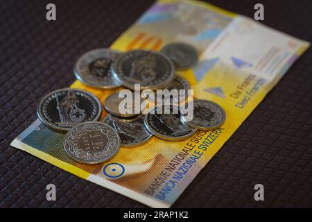 Schweizer Franken-Münzen und alte Banknote lagen auf einem braunen strukturierten Hintergrund. Stockfoto