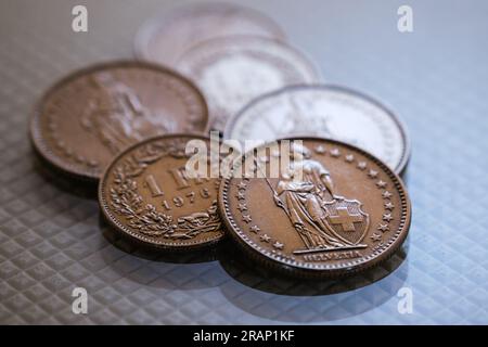 Ein paar Schweizer-Franken-Münzen, die auf einer glänzenden, weiß strukturierten Basis liegen. Stockfoto