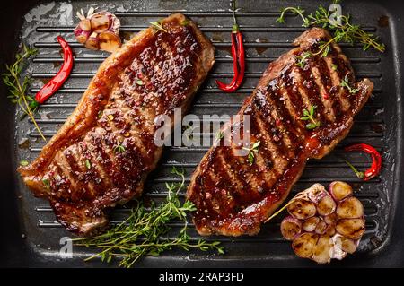 Gegrilltes Striploin Steak mit Gewürzen und Kräutern auf einer Eisentopf. Das Strip Steak, auch bekannt als New York Strip. Stockfoto