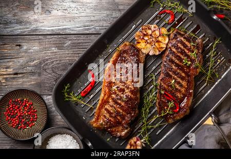 Gegrilltes Striploin Steak mit Gewürzen und Kräutern auf einer Eisentopf. Das Strip Steak, auch bekannt als New York Strip. Stockfoto