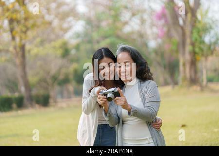 Mutter und Tochter eines asiatischen Teenagers gehen mit Kamera in den Park, um Erinnerungen festzuhalten Stockfoto