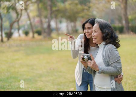 Mutter und Tochter eines asiatischen Teenagers gehen mit Kamera in den Park, um Erinnerungen festzuhalten Stockfoto