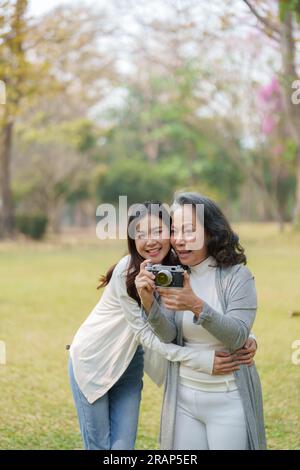 Mutter und Tochter eines asiatischen Teenagers gehen mit Kamera in den Park, um Erinnerungen festzuhalten Stockfoto