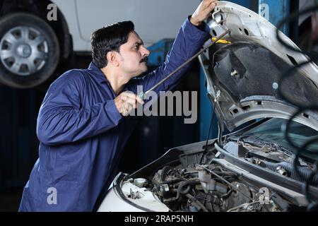 Porträt eines Automechanikers im Schnurrbart bei der Reparatur und Prüfung des Automotors. Ein Autospezialist verwendet Reparaturwerkzeuge. Ein Mechaniker Stockfoto