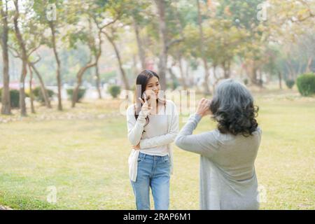 Mutter und Tochter eines asiatischen Teenagers gehen mit Kamera in den Park, um Erinnerungen festzuhalten Stockfoto