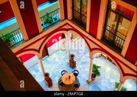 Sevilla, Spanien - 20. Januar 2023: Vincci La Rabida. Eine farbenfrohe Hotellobby, von oben gesehen. Ein Tisch mit Stühlen und architektonischen Säulen ist in t vorhanden Stockfoto