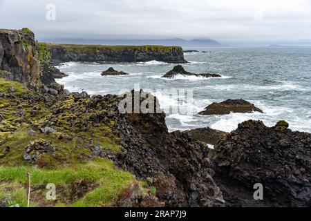 Wellen, die sich an schwarzen Basaltklippen an den Arnarstapi-Klippen auf der Halbinsel Snæfellsnes, Island, wühlen Stockfoto