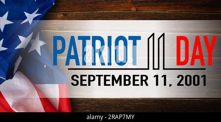 Die Worte Patriot Day 09.11.01 wurden mit silbernen Metallbuchstaben auf Holzbrettfläche mit zerknitterter us-Flagge unten mit Nahaufnahme diagonaler Perspektive gelegt Stockfoto
