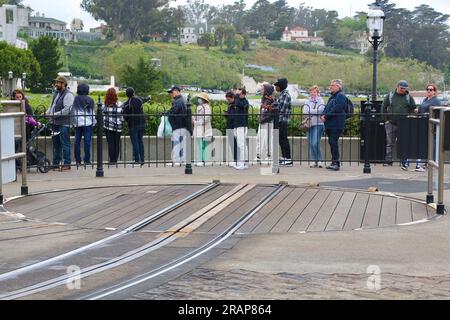 Touristen warten an einem kalten Tag im Mai in San Francisco Kalifornien USA in der Warteschlange am Hyde and Beach Cable Car Terminal mit einer leeren Drehscheibe Stockfoto