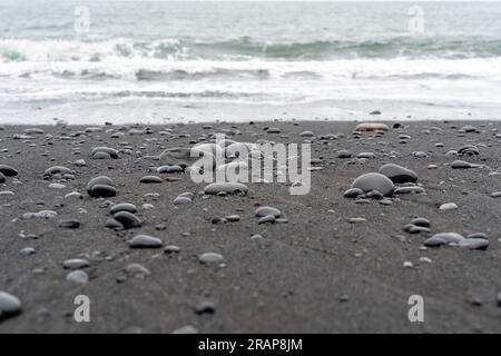 Wellen, die sich gegen Reynisfjara Black Sand Beach in Island wühlen Stockfoto