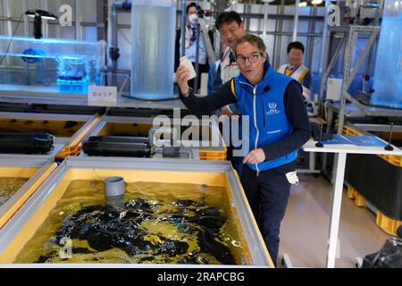 Futaba, Japan. 5. Juli 2023. Rafael Mariano Grossi, Generaldirektor der Internationalen Atomenergie-Organisation, zeigt eine leere Flasche, nachdem er Flunder in einem mit behandeltem Abwasser gefüllten Fischtank in einem Labor gefüttert hat, während er das beschädigte Kernkraftwerk Fukushima in Okuma, Nordosten Japans, am Mittwoch, den 5. Juli 2023 besuchte. Hinter ihm ist Tokyo Electric Power Co Präsident Tomoaki Kobayakawa. (Credit Image: © POOL via ZUMA Press Wire) NUR REDAKTIONELLE VERWENDUNG! Nicht für den kommerziellen GEBRAUCH! Stockfoto