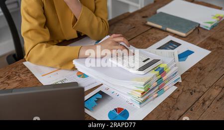 Nahaufnahme der Hände einer Geschäftsfrau mit einem Taschenrechner, um die Finanzen und Einnahmen des Unternehmens sowie das Budget zu prüfen. Geschäftsfrau, die die monatlichen Ausgaben berechnet Stockfoto