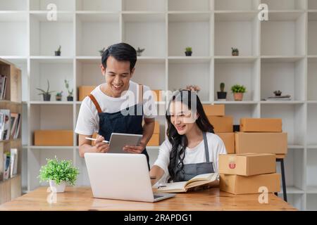 Ein junges asiatisches Paar, das nach der neuen Bestellung des Kunden glücklich ist. Überraschungs- und Schockgesicht des asiatischen Paares, das seinen Online-Shop erfolgreich verkauft hat. Online Stockfoto