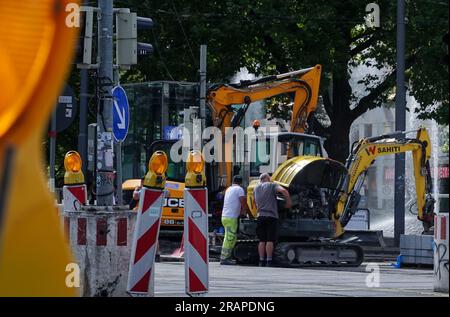 04. Juli 2023, Bayern, München: Arbeiter stehen neben einem Bagger auf einer Baustelle am Sendlinger Tor im Stadtzentrum. Foto: Sabina Crisan/dpa Stockfoto