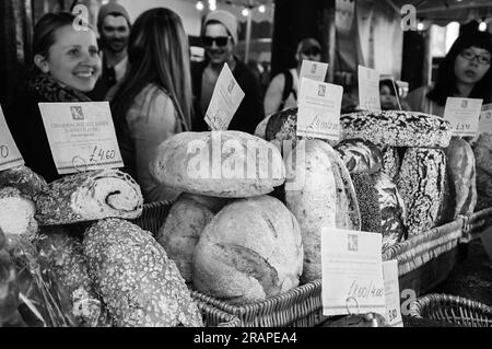 LONDON, ENGLAND, Großbritannien - 3. MAI 2014: Nicht identifizierte junge Menschen kaufen Brot in der Karaway Bakery auf dem berühmten Borough Market. Schwarzes, weißes historisches Foto. Stockfoto