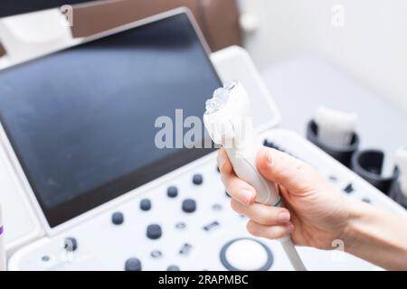 Weibliche Arzthand mit medizinischem Gel zum Ultraschallsensor des Ultraschallgerätes in der Klinik. Ultraschalldiagnostik. Gesundheitswesen A Stockfoto