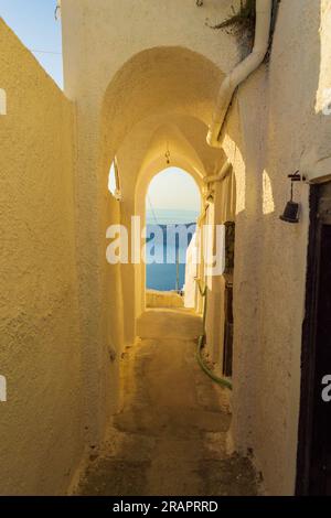 Bogenförmiger schmaler Durchgang, der zum Rand der Caldera in Imerovigli, Santorini, Griechenland führt. Das gehobene Dorf Imerovigli liegt auf einer Klippe mit Blick auf Caldera Stockfoto