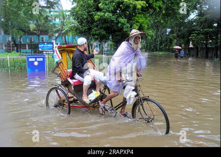 Bei starkem Regen machen sich die Leute auf den Weg. Die unaufhörlichen Regenfälle der letzten Tage haben in Sylhet zu Problemen mit der Wassergewinnung geführt, wobei viele Straßen unter Wasser waren. Aufgrund ungeplanter Baumaßnahmen und eines schlechten Abflusssystems werden diese wasserdurchlässigen Bereiche bei starken Regenfällen und sogar leichten Regenfällen überflutet, so die Einheimischen. Sylhet, Bangladesch. Stockfoto