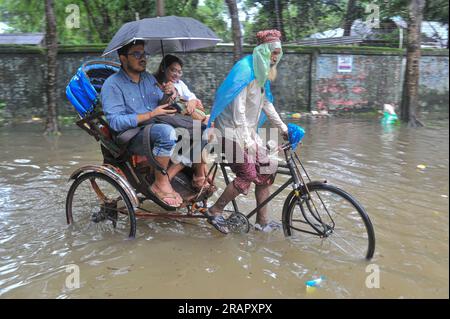 Bei starkem Regen machen sich die Leute auf den Weg. Die unaufhörlichen Regenfälle der letzten Tage haben in Sylhet zu Problemen mit der Wassergewinnung geführt, wobei viele Straßen unter Wasser waren. Aufgrund ungeplanter Baumaßnahmen und eines schlechten Abflusssystems werden diese wasserdurchlässigen Bereiche bei starken Regenfällen und sogar leichten Regenfällen überflutet, so die Einheimischen. Sylhet, Bangladesch. Stockfoto