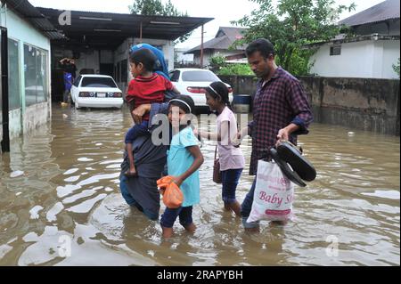 Bei starkem Regen machen sich die Leute auf den Weg. Die unaufhörlichen Regenfälle der letzten Tage haben in Sylhet zu Problemen mit der Wassergewinnung geführt, wobei viele Straßen unter Wasser waren. Aufgrund ungeplanter Baumaßnahmen und eines schlechten Abflusssystems werden diese wasserdurchlässigen Bereiche bei starken Regenfällen und sogar leichten Regenfällen überflutet, so die Einheimischen. Sylhet, Bangladesch. Stockfoto