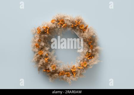 Thanksgiving-Kranz mit trockenen natürlichen Materialien und Orangenbeeren auf blauem Hintergrund. Draufsicht. Speicherplatz kopieren. Minimalismus. Stockfoto